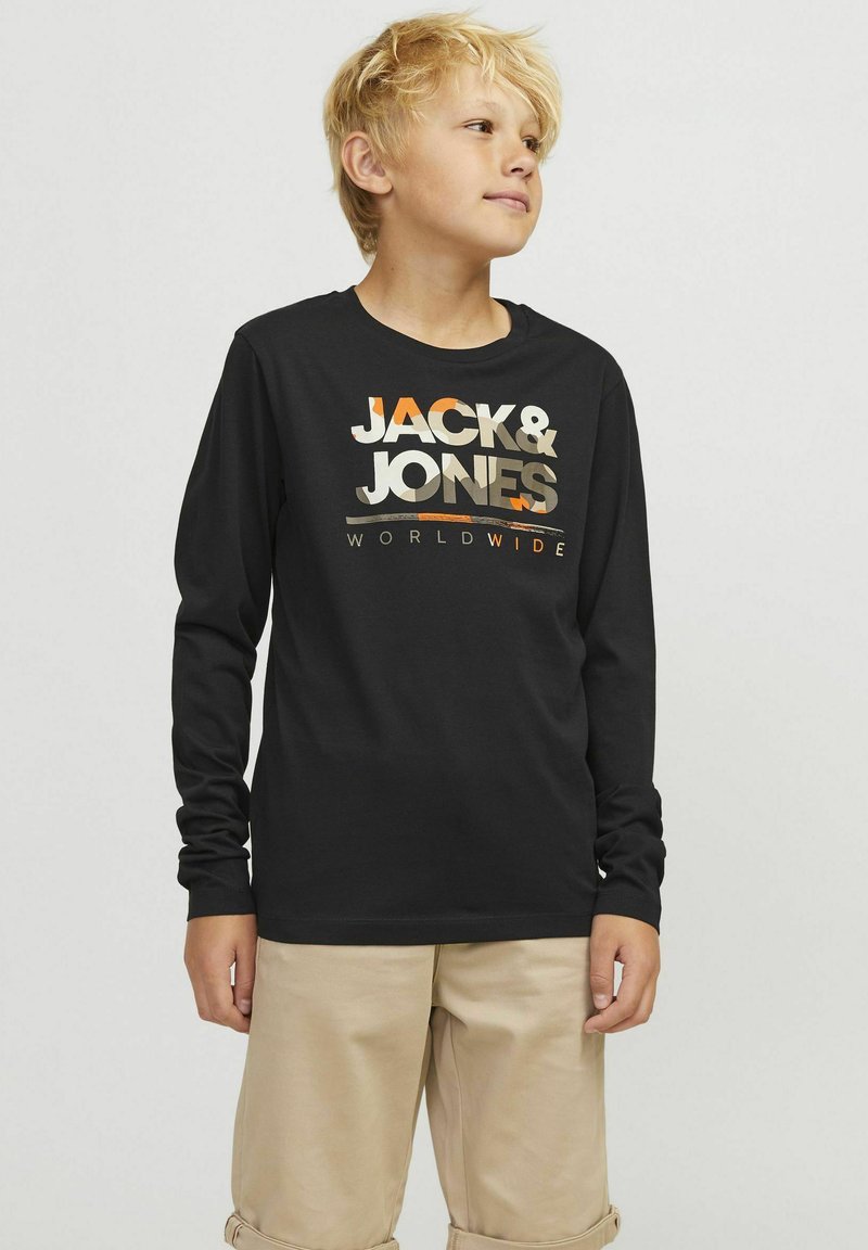 Crna majica dugih rukava s logom "JACK & JONES" u metalnim nijansama sprijeda; uparen s svijetlim bež kratkim hlačama. Mekani materijal i ležeran kroj.