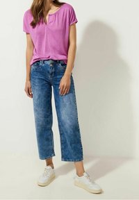 Rosa kortärmad topp med rundad halsringning, kombinerad med ljusblå vida jeans och vita sneakers. Slinky tyg, avslappnad passform.