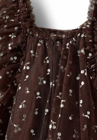 Barna tüll anyag textúrált felülettel, ezüst virágmintákkal és fodros szélekkel a nyakkivágásnál.