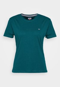 Turkusowa koszulka z krótkim rękawem, z okrągłym dekoltem, z małym logo Tommy Jeans na lewej piersi i paskowanym detalem w dekolcie.