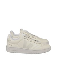 Krämfärgade lädersneakers med låg toppdesign, som har en strukturerad ovandel, perforerade detaljer och subtil branding på sidan.