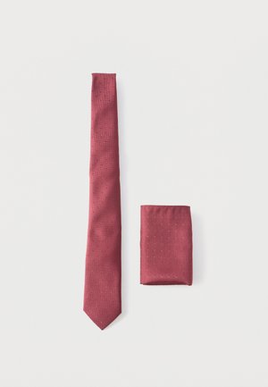 Cravate rouge et pochette assortie pliée avec un motif à petits points subtils, posées à plat sur un fond blanc.
