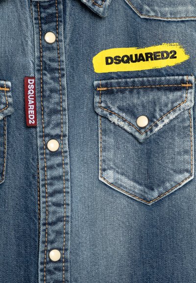 Camicia in denim con un lavaggio azzurro chiaro, chiusura con bottoni, due tasche sul petto con bottoni, logo DSQUARED2 giallo e cuciture a contrasto.