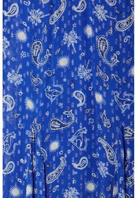 Tissu bleu avec des motifs cachemire blancs, des coqs stylisés, des palmiers, des étoiles et des formes de soleil dans un motif répétitif.