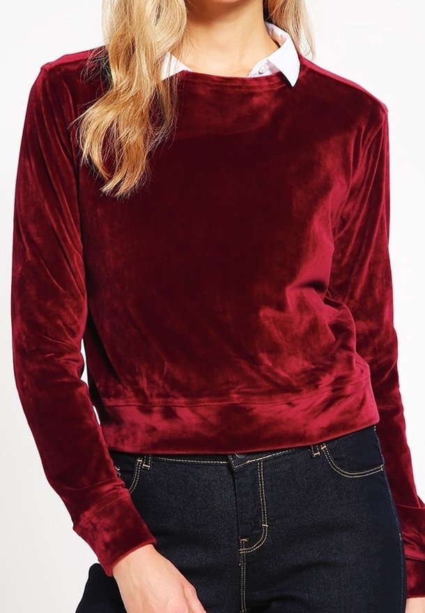 Suéter de terciopelo burdeos con mangas largas y escote redondeado, superpuesto a una camisa blanca con cuello. Textura suave y lisa.