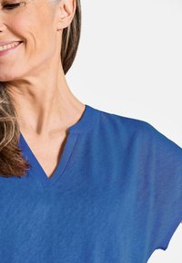 Blauwe V-hals T-shirt gemaakt van zachte stof met korte mouwen, met een subtiele textuur en een minimalistisch neklijnontwerp.