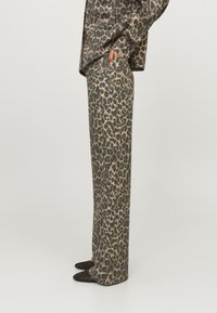 Leopard print tailored suit pants in dark brown and beige fabric. Straight-leg design with side pockets and a smooth texture.
