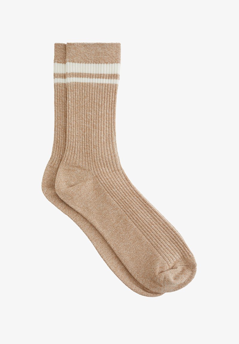 Calcetines beige de punto con textura acanalada y dos rayas blancas en la parte superior. Material suave, altura hasta la mitad del gemelo y forma estructurada.