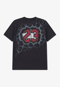 Μαύρο βαμβακερό μπλουζάκι με μεγάλο γραφικό τύπωμα του αριθμού «23» σε κόκκινο και λευκό, περιτριγυρισμένο από σπασμένο σχέδιο.