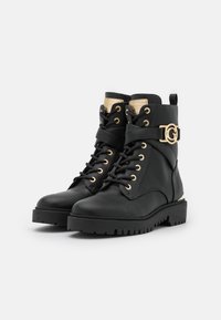 Bottines en cuir noir avec une finition texturée, accents en métal doré, laçage à l'avant et design de semelle robuste. Présente un détail de logo.