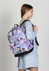 Mochila temática de Disney con un diseño púrpura que presenta ilustraciones de princesas, acentos negros, bolsillos con cremallera y correas ajustables.