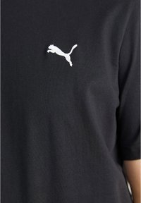 Schwarzes Baumwoll-T-Shirt mit einem weißen, auf der linken Brustseite eingestuften Puma-Logo. Kurze Ärmel und eine glatte, einfarbige Struktur.