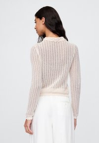 Leichter, gerippter Strickpullover in Creme, mit einem geschwungenen Ausschnitt und Bündchen, tailliert und mit langen Ärmeln.