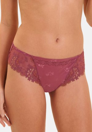 Woman wearing mauve lace and sheer floral patterned underwear, shown from waist to upper thighs on a light background.