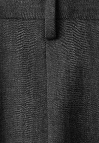 Tkanina w wzór pepitki w ciemnoszarej i czarnej kolorystyce. Materiał ma gładką teksturę i posiada dopasowany pas w talii.