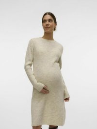 Stickad gravidklänning i ljusbeige, med ribbat mönster, långa ärmar och en avslappnad passform som rymmer en växande mage.