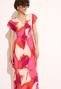 Maxi sukienka z lekkiego materiału, zdobiona intensywnym kwiatowym wzorem w odcieniach różu, pomarańczu i bieli; głęboki dekolt w kształcie litery V i krótkie rękawy.