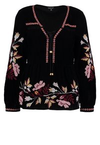 Blouse en velours noir à manches longues, ornée de broderies florales colorées, avec un décolleté en V et un cordon de serrage avec des accents dorés.