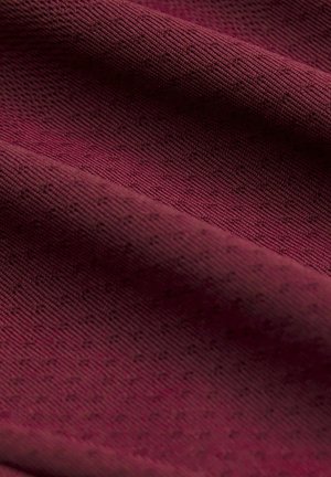 Tissu rouge profond avec un motif tricoté texturé, délicatement plié pour montrer un fin côtelé doux et des points légèrement en relief sur toute la surface.