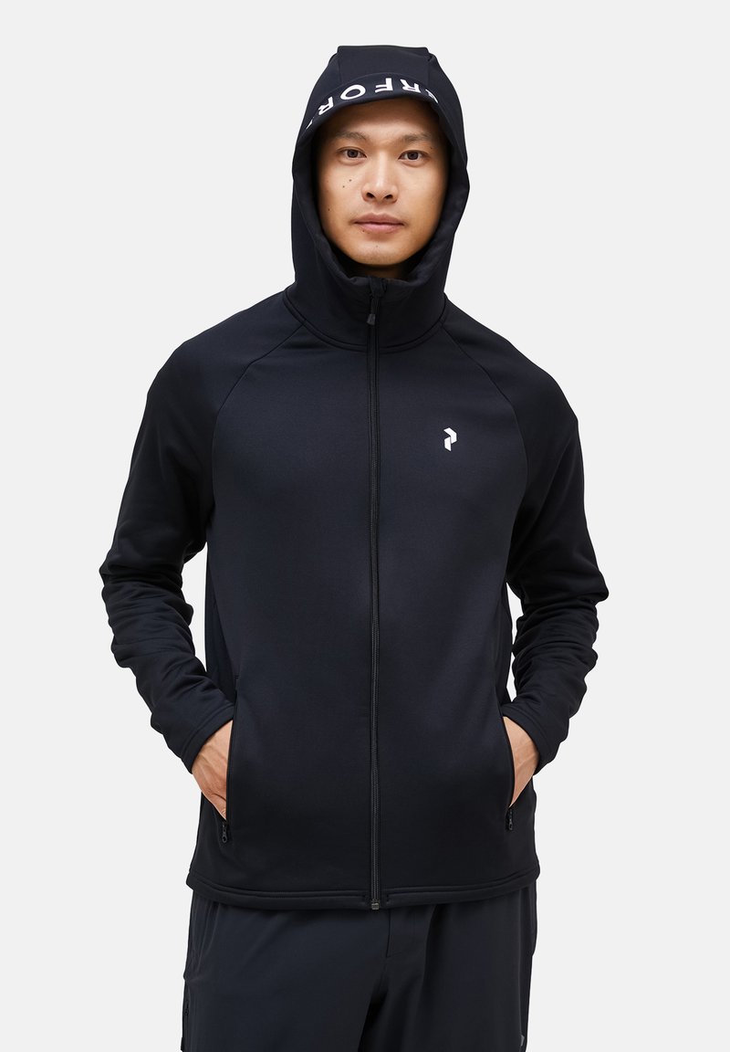 Černá mikina na zip s vysokým límcem a kapucí na šňůrku. Obsahuje bílé logo na hrudi a přední kapsy. Elastický, hladký materiál.