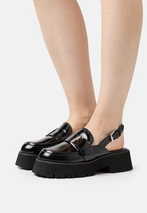 Chaussures slingback en cuir verni noir avec une semelle épaisse et un détail de boucle. Présente une semelle extérieure en caoutchouc texturé noir pour une adhérence optimale.