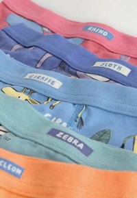 Collezione di t-shirt in cotone colorate con stampe a tema animale. Presentano colletti rosa, blu, verdi e arancioni con etichette: "Rinoceronte," "Bradipo," "Giraffa," "Zebra."
