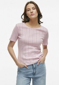T-shirt in magenta chiaro a maglia con maniche corte, caratterizzato da un motivo testurizzato e un collo rotondo, abbinato a jeans azzurri chiari.
