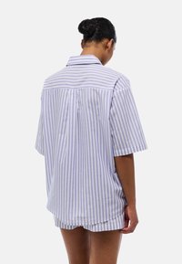 Chemise à manches courtes, surdimensionnée, à rayures verticales violettes claires et blanches, avec une couture de garcette au dos et une coupe détendue.
