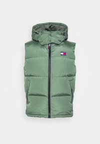 Zelená prošívaná vesta s kapucí, vybavená předním zipem a bočními kapsami, vyznačuje se logem na levém horním rohu.