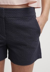 Námořnické, texturované šortky s geometrickým vzorem, s plochým pasem a bočními kapsami pro praktičnost.