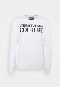 Bílá mikina s dlouhými rukávy a kulatým výstřihem. Na přední straně je černý potisk s logem "VERSACE JEANS COUTURE". Měkká textilie.