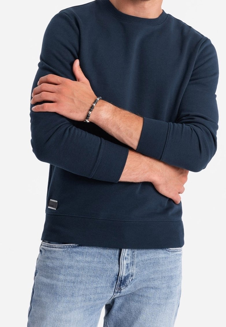 Marinblå sweatshirt med rund halsringning, ribbade ärmslut och nederkant, tillverkad av mjukt material. Har en liten logotag nära botten.