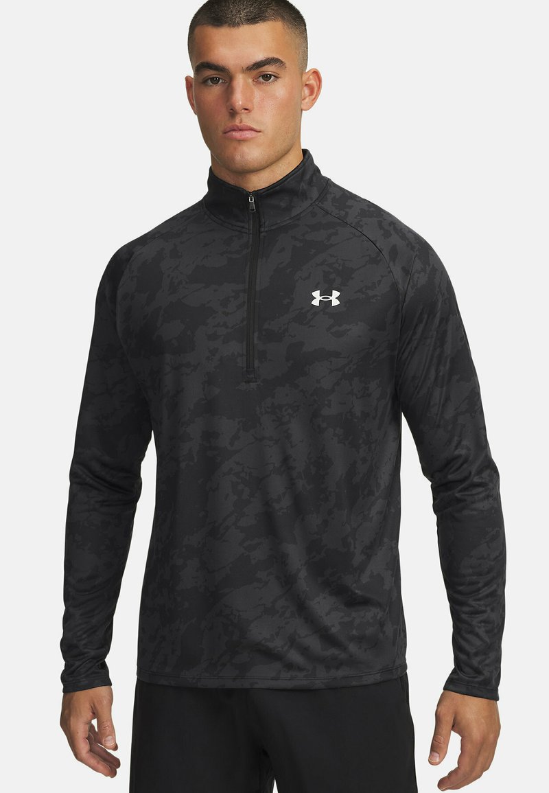 Zwart atletisch shirt met lange mouwen en een halve rits kraag. Beschikt over een camouflagepatroon, lichtgewicht stof en een klein wit logo op de borst.