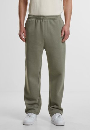 Olivegrüne Sweatpants aus einer weichen Baumwollmischung, mit elastischem Bund und Seitentaschen, kombiniert mit weißen Sneakers.