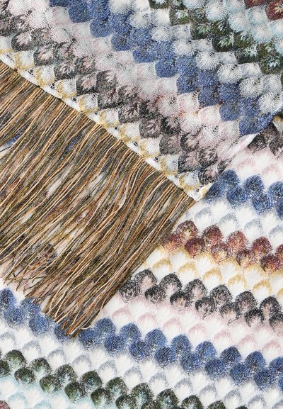 Tissu tricoté multicolore avec un motif en losange et des tons dorés, bleus et verts, doté de longs pompons dorés brillants sur un bord.