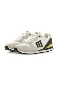 Zapatillas en cuero beige y blanco con gamuza gris, con un logotipo negro, puntera redonda, suela plana y un acento amarillo en el talón.