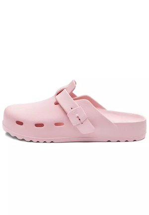 Jasnoróżowe klapki typu slip-on z regulowanym paskiem, otworami wentylacyjnymi przy podeszwie i teksturowanym bieżnikiem zapewniającym przyczepność.
