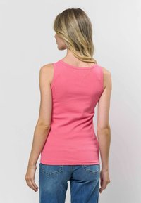 Roz�ā ribota bez Piedurknēm top ar apaļu dekoltē, saskaņots ar ziliem džinsiem. Gluda tekstūra, pieglauta siluets.