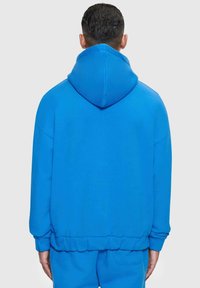 Blaue Kapuzen-Sweatjacke mit entspannter Passform, gerippten Bündchen und Saum. Glatte Textur mit einer großen Kapuze auf der Rückseite.