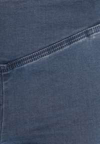 Tejido de denim en azul oscuro con una textura suave. Presenta un ligero brillo y costuras visibles a lo largo del borde, destacando un diseño limpio.