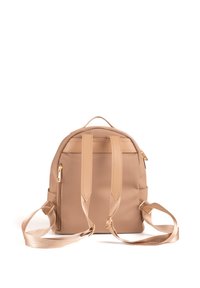 Zaino beige con spallacci regolabili, materiale resistente, dettagli in metallo dorato e forma arrotondata. Presenta tasche laterali e una maniglia superiore.