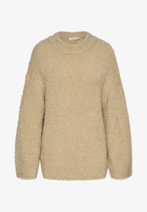 Pull en beige duveteux avec un col rond, des épaules tombantes et une texture douce. Présente une coupe décontractée et des poignets côtelés aux manches.