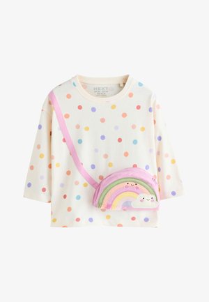 Cremefarvet langærmet skjorte med flerfarvede polkaprikker og en fastgjort lyserød crossbody taske formet som en smilende regnbue og sky.