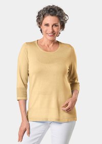 Gelber Strickpullover mit einem Rundhalsausschnitt und Dreiviertelärmeln, der ribbelige Akzente an den Bündchen und am Saum aufweist. Glatte Textur.