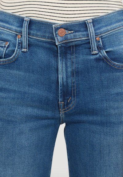 Jeans in denim blu con vita alta, chiusura a bottone in rame e dettagli a punto singolo lungo le cuciture e le tasche.