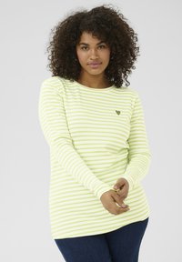 Chemise à manches longues rayée vert clair et blanche avec un petit cœur sur la poitrine, fabriquée en tissu doux et extensible.