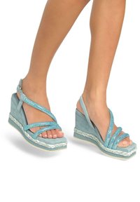 Sandali con zeppa in suede azzurro chiaro, caratterizzati da cinturini glitterati e una suola intermedia in juta intrecciata. Design con punta aperta e fibbie regolabili.