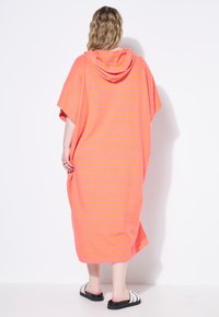 Vestido con capucha de gran tamaño en rosa con rayas amarillas, que presenta mangas cortas y un corte relajado. Hecho de una tela suave, llega hasta la mitad de la pantorrilla.