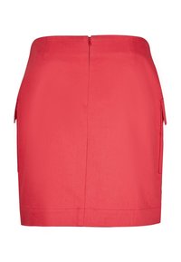Falda roja ajustada con bolsillos laterales, textura suave, cierre de cremallera en la parte trasera y un diseño a medida. Termina justo por encima de la rodilla.
