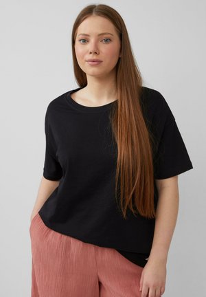T-shirt en coton noir avec une coupe décontractée, des manches courtes et un col rond, associé à un pantalon plissé rose texturé.